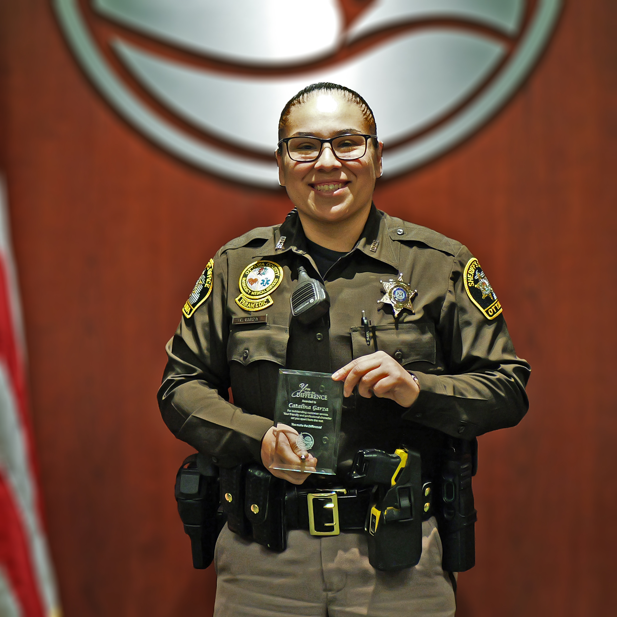 Deputy poses with award in front of Ottawa County Logo