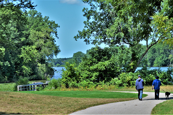 A couple walks their dog next to Connor Bayou in the summer time