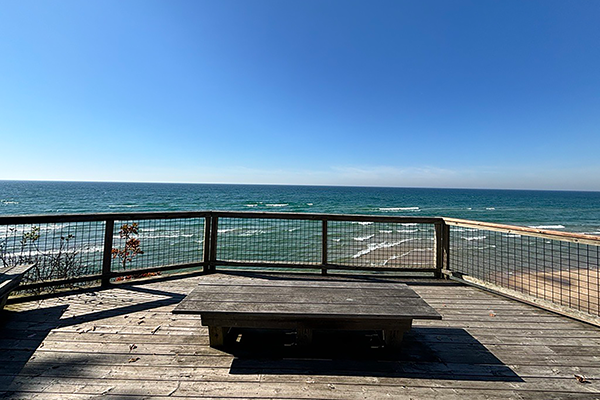An observation deck with a bench looks out over the calm waters of Lake Michigan