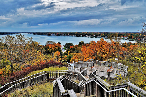 The view from the top of a large hill overlooking Big Bay; A boardwalk with an observation deck and benches descends into the valley.